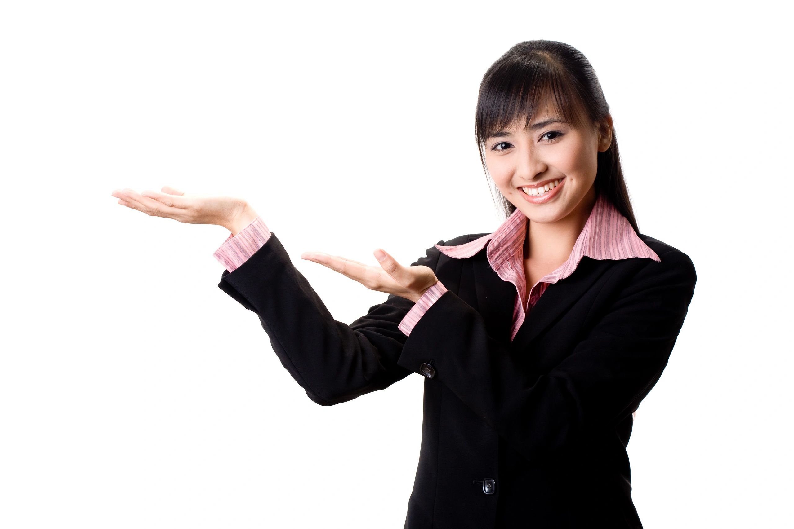 A woman in a black suit smiles and gestures with her hands, showcasing something to the viewer.